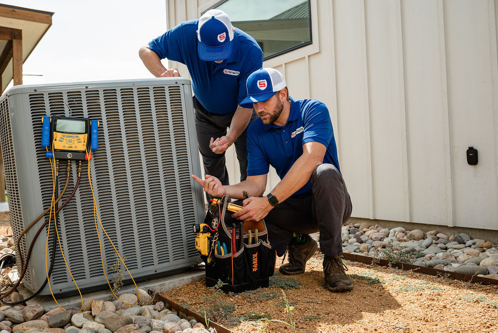 Two Strittmatter employees performing AC installation outside a home in Denton, TX