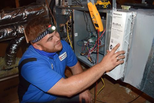 Technician installing air filtration system in a home's HVAC.