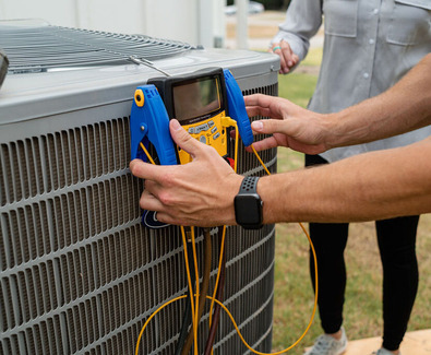 Technician testing an outdoor HVAC unit.