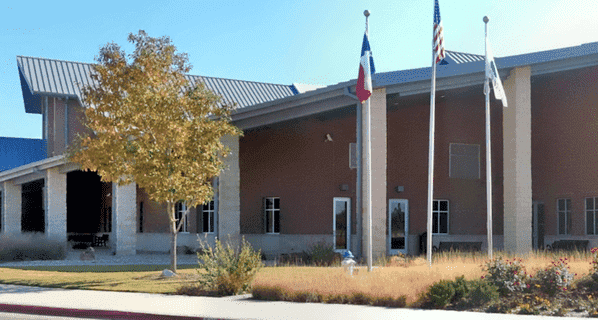 Image of a large public building with flag poles in front, in Flower Mound, TX.