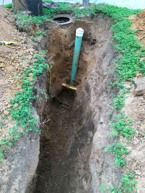 A trench dug in a yard with pipe in it.