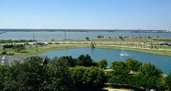 View of Lake Dallas, TX, with green trees in foreground.
