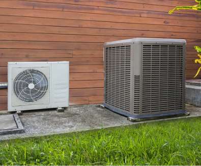 Two HVAC units outside a home with natural wood siding.