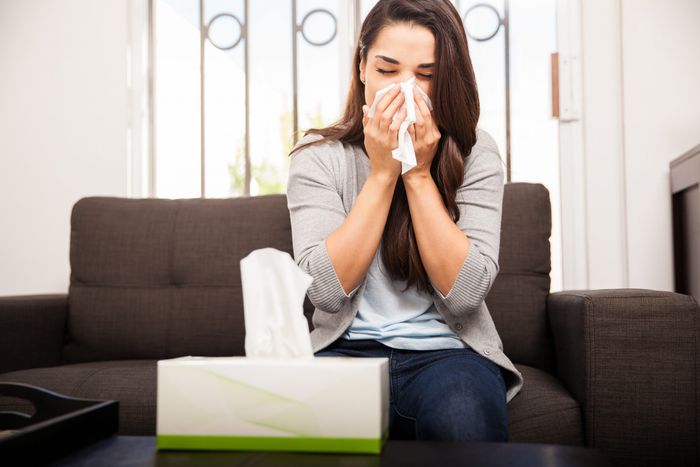 women with flu using tissue paper while sneezing