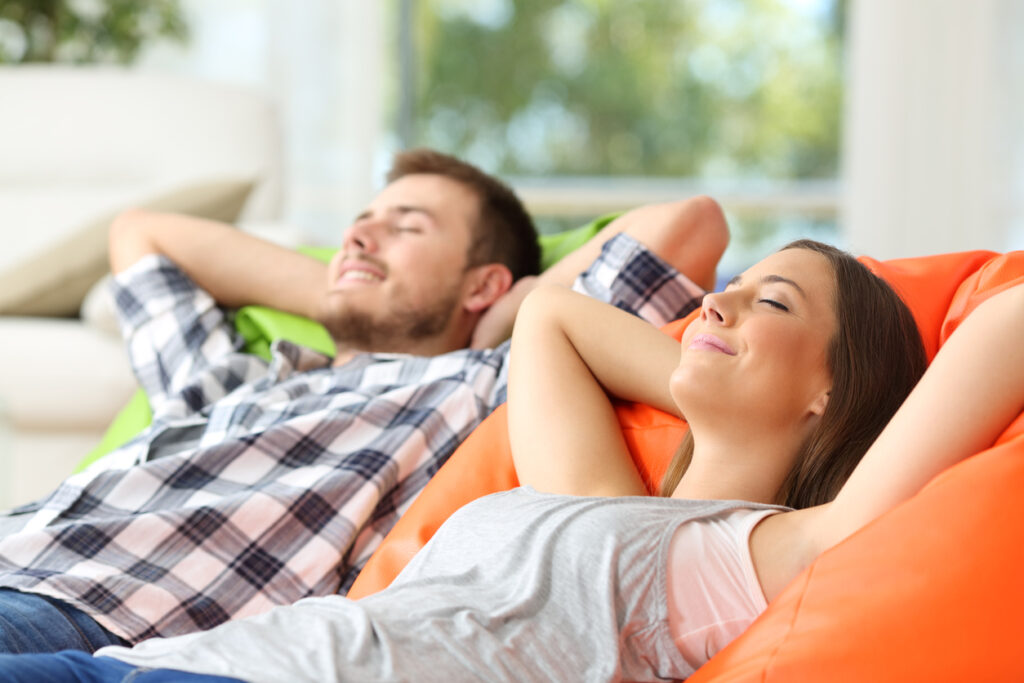 Man and woman relaxing lying on comfortable poufs in the living room at home.