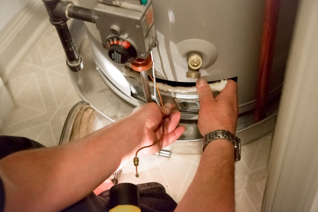 Close up of plumber's hands as he performs maintenance on a water heater.