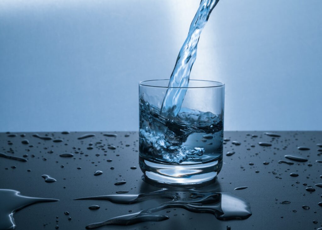 Water pouring into a glass setting on a counter.